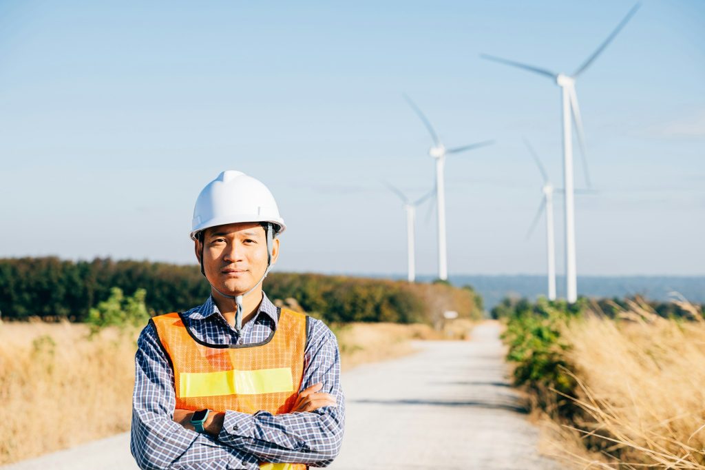 Technician helmet-clad engineer inspects windmill farm
