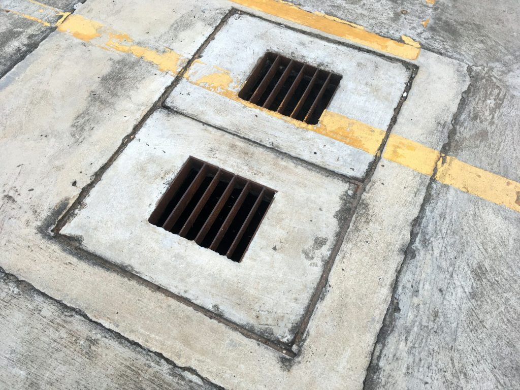 The iron grate of the drainage system on the footpath